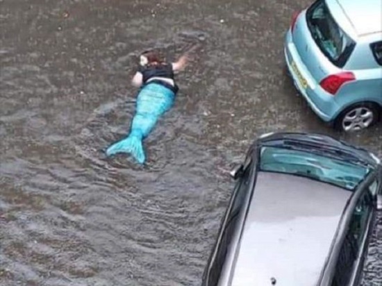 findingfun:womaninmermaidcostumegoesforaleisurelyswiminfloodedglasgowstreet